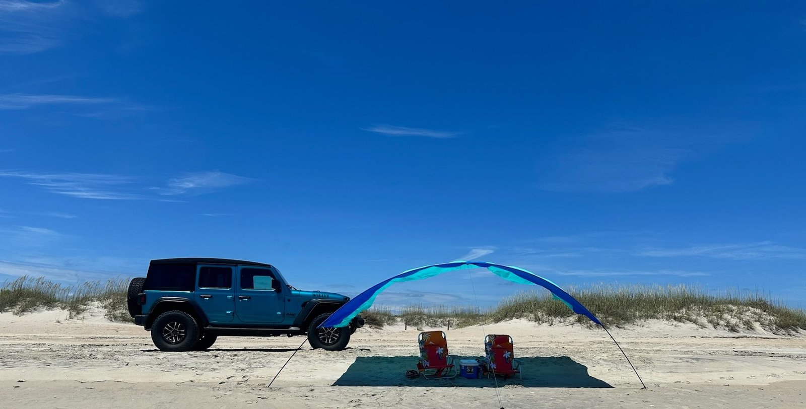 Outer Banks 4WD Jeep Wrangler rental parked on Carova Beach with shade canopy and chairs on the sand