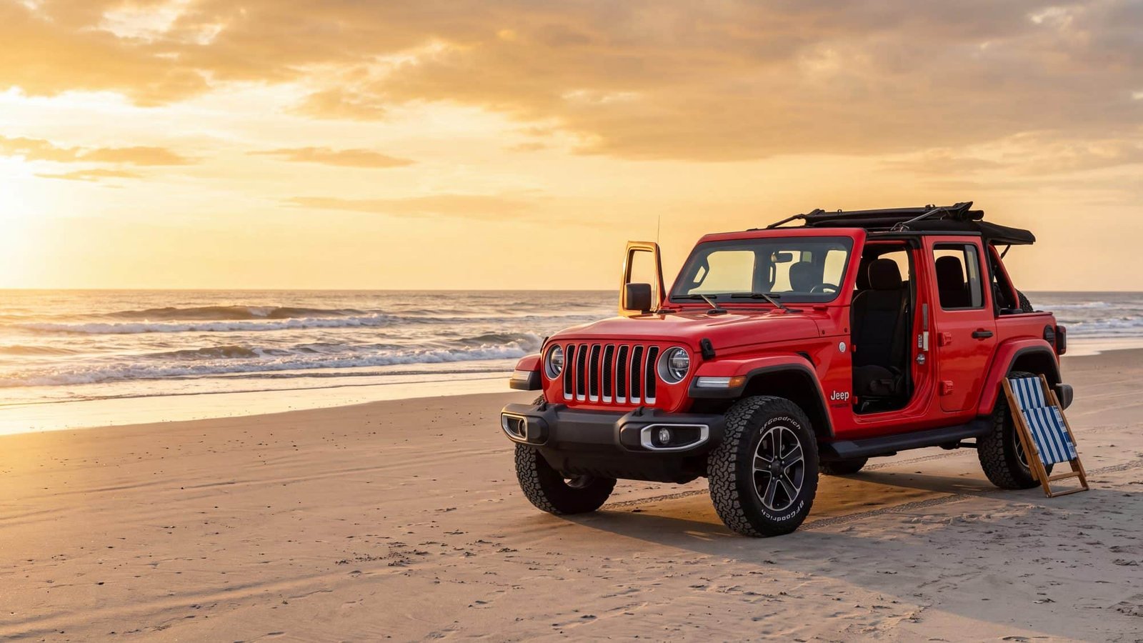 A red Jeep Wrangler JL Unlimited parked on hard sand at golden hour with its driver door open and a folded beach chair leaning on the rear wheel — Outer Banks, NC